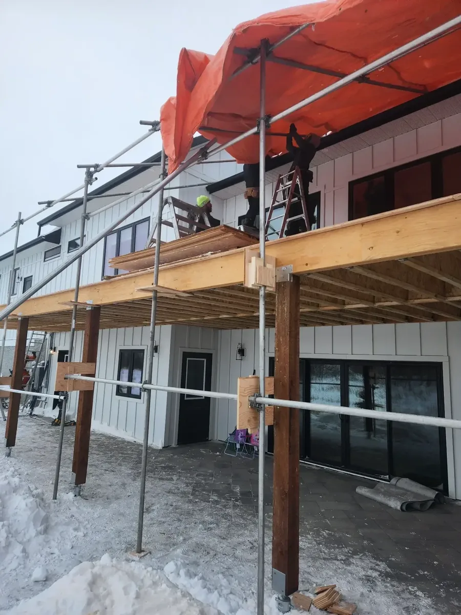 Tube and clamp scaffolding with orange tarp enclosure deck build Saskatoon